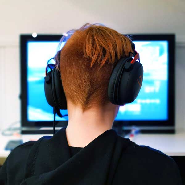 Jugendliche mit Kopfhörern sitzt vor einem Bildschirm